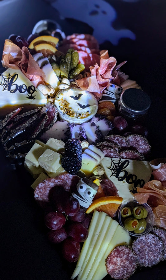 Halloween-themed charcuterie board with various treats and decorations on a dark background.